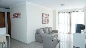sala de estar blanca con sofá y TV en Golden Flat en João Pessoa