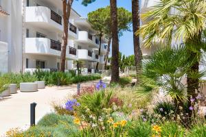 a garden in front of a building with palm trees and flowers at Inturotel Esmeralda Park in Cala d´Or