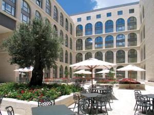 um pátio com mesas e guarda-sóis em frente a um edifício em Grand Court Hotel em Jerusalém