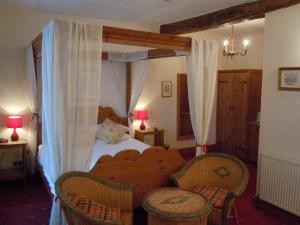 a bedroom with a canopy bed with two chairs at The New Inn in Thornton Dale