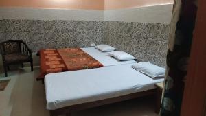 two beds in a small room with a chair at Vidya Guest House in Katra