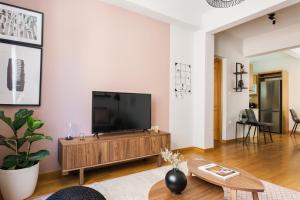 un soggiorno con TV a schermo piatto su un centro di intrattenimento in legno di Delightful 1BD Apartment in Plaka by UPSTREET ad Atene