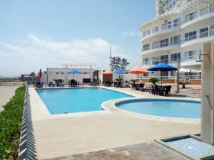 een zwembad met tafels en parasols naast een gebouw bij Villa Altamar in Playas