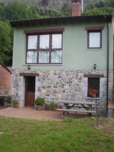 una casa con una mesa de picnic delante de ella en Vivienda vacacional La Poza la Braña, en Llanes