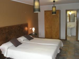 a bedroom with two white beds and a bathroom at La Senda del Casaño in Canales