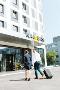 due uomini che camminano davanti a un palazzo con i bagagli di Hotel Rainers21 a Brunn am Gebirge
