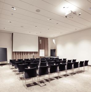 a conference room with chairs and a podium and a screen at Hotel Rainers21 in Brunn am Gebirge