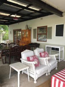 eine Terrasse mit weißen Stühlen, einem Tisch und einem Esszimmer in der Unterkunft Olive Manor Guest House in Newcastle