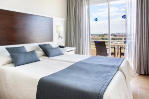 ein Hotelzimmer mit zwei Betten, einem Tisch und einem Fenster in der Unterkunft Grupotel Amapola in Playa de Muro