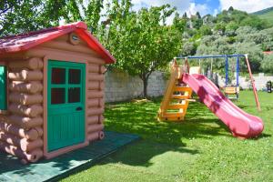 a playground with a house and a slide at Villa Dolphin Apartments in Petrovac na Moru