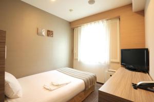 a hotel room with a bed and a television at Smile Hotel Kawaguchi in Kawaguchi