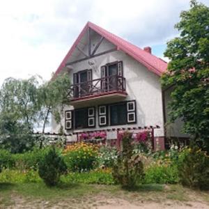 ゴニョンツにあるŁosiowy Kątのバルコニー付きの家、花が目の前に咲いています。
