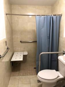 uma casa de banho com um WC e um chuveiro com uma cortina de chuveiro azul em Ramona Motel em Miami