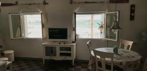 a living room with a table and a television and two windows at Auténtica vivienda de pescadores en primerísima línea de playa in Villajoyosa