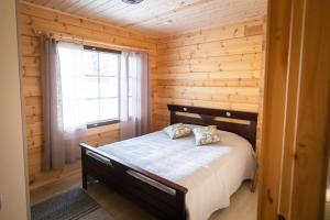 a bedroom with a bed in a wooden cabin at Villa Vahtivuori in Rantasalmi