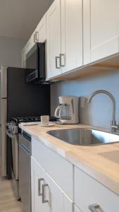 uma cozinha com um lavatório de aço inoxidável e armários brancos em A Wave Inn - Montauk em Montauk