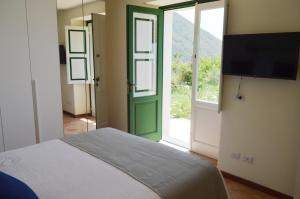 1 dormitorio con 1 cama con puerta verde y TV en Orizzonte Relais, en Leni