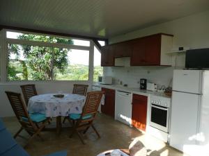 a kitchen with a table and chairs and a kitchen with a window at BUNGALOW DU VOYAGEUR in Le Marin