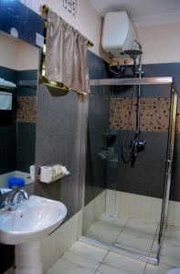 y baño con ducha y lavamanos. en Tulia Boutique Hotel & Spa en Arusha