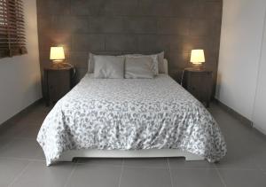 a bed with a black and white comforter and two lamps at Galdar GC Vistas al Mar in Gáldar +32 photos
