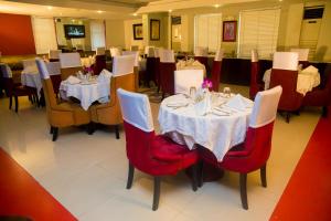 BW Starfire Hotel في إيكيجا: غرفة طعام مع طاولات بيضاء وكراسي حمراء