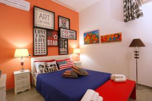 ナルドにあるA Casa di Giorgia "Beautiful House" a Nardò nel Salentoのベッドルーム1室(青いベッド1台付)が備わります。壁には絵画が飾られています。