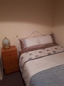 a bedroom with a bed and a wooden nightstand with a bed sidx sidx sidx at 3 MacNean Park in Belcoo