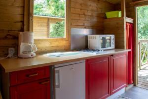 una cocina con armarios rojos y un aparato blanco en Camping des Rochers des Parcs, en Clécy