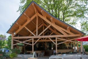 un grand bâtiment en bois avec un toit dans l'établissement Camping des Rochers des Parcs, à Clécy