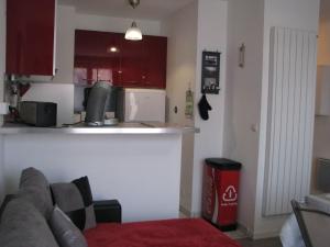 a kitchen with red cabinets and a couch in a room at LES BERNACHES in Le Crotoy