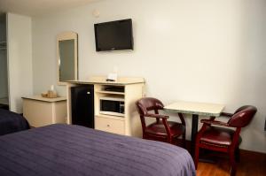 een hotelkamer met een bed en twee stoelen en een televisie bij Economy Inn in West Palm Beach