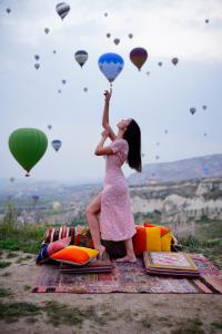 a young girl in a pink dress holding up balloons at Kayatas Cave Suites in Goreme