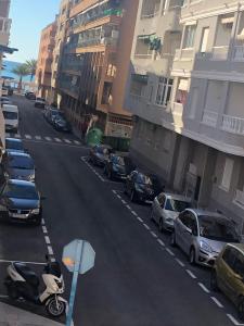 ulica z zaparkowanymi samochodami i skuterem na drodze w obiekcie Gallud Apartament w mieście Torrevieja