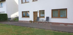 una casa blanca con 2 sillas y una puerta en Haus Anna, en Kelberg