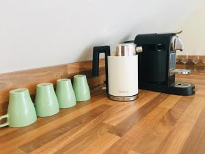 a row of green cups next to a coffee maker at Apartment Urlaubsrausch am Möhnesee in Möhnesee