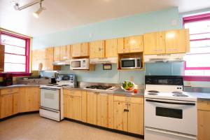 a kitchen with white appliances and wooden cabinets at Ocean Island Inn | Backpackers | Suites in Victoria
