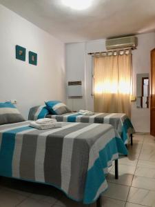 2 camas en una habitación con sábanas azules y blancas en Ochomin Hostel, en San Martín del Tesorillo