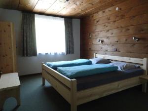 ein Schlafzimmer mit einem Bett mit einer Holzwand in der Unterkunft Haus Martine in Raggal