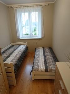 sypialnia z 2 łóżkami i oknem w obiekcie Apartament BRYZA w mieście Darłowo