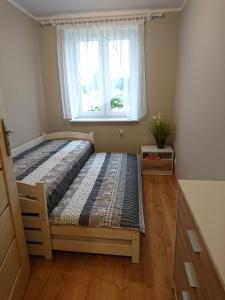 a bedroom with a bed with a window at Apartament BRYZA in Darłowo