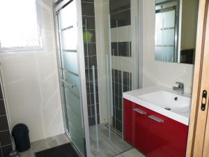 ein Bad mit einem roten Waschbecken und einer Dusche in der Unterkunft Les mouettes in Les Herbiers