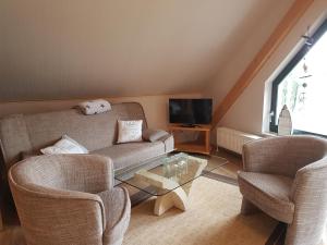 a living room with a couch and two chairs and a tv at Havel-Pension Kruse in Havelberg