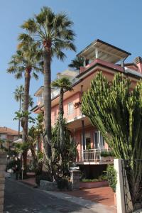 ボルディゲーラにあるVilla Mirellaのヤシの木が目の前に広がるピンクの家