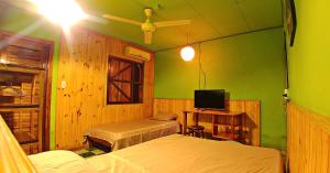 1 dormitorio con 2 camas y TV. en Cabinas Casa Dolce Vita en Puerto Viejo