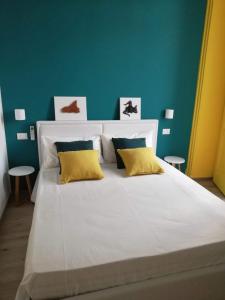 un grande letto bianco con due cuscini gialli sopra di GH Rooms Catania a Catania
