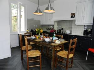eine Küche mit einem Holztisch und Stühlen in der Unterkunft Chez Paulette in Pont-Audemer