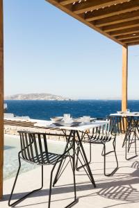 einen Tisch und Stühle auf einer Terrasse mit Meerblick in der Unterkunft Mykonos Soul Luxury Suites in Agios Stefanos