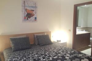 een slaapkamer met een bed met 2 kussens en een spiegel bij Bel appartement avec vue sur mer in Arona