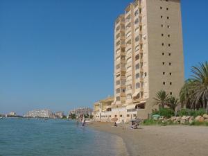 a large building on the beach with people in the water at Apartamentos Neptuno GL V.v. in La Manga del Mar Menor