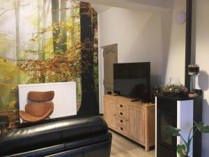 uma sala de estar com uma cadeira de couro e uma televisão em Villa Schoon em Geraardsbergen